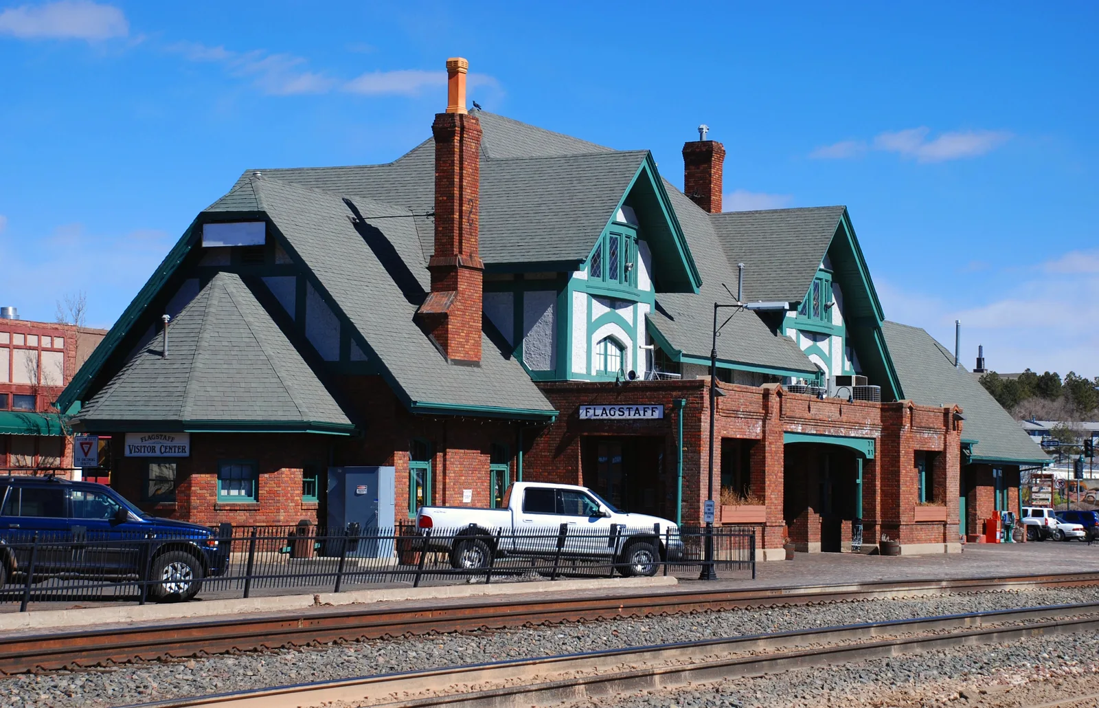 Historic Flagstaff train depot and visitor center beside railroad tracks under a clear sky.
